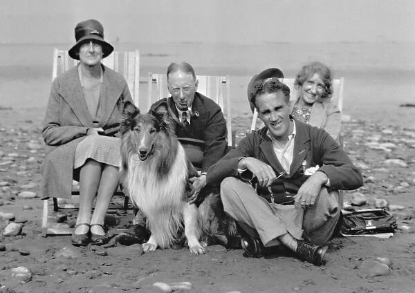 Four people on beach with collie dog