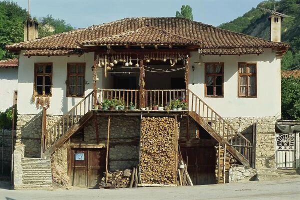 A traditional house with a log store, and gourds and chillies drying in the sun