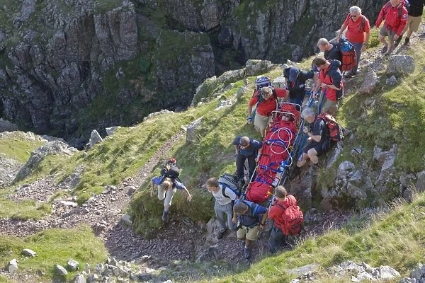 Members of Langdale Ambleside Mountain Rescue Team carrying an injured walker from the fells in Langdale Cumbria