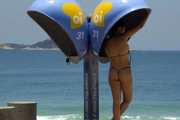 Woman in bikini calling from a public telephone at Ipanema beach, Rio de Janeiro, Brazil