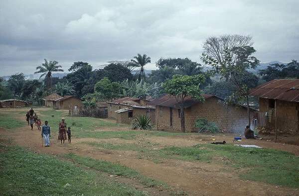 20070633. ANGOLA Vige Mud brick village houses with people on unmade road outside