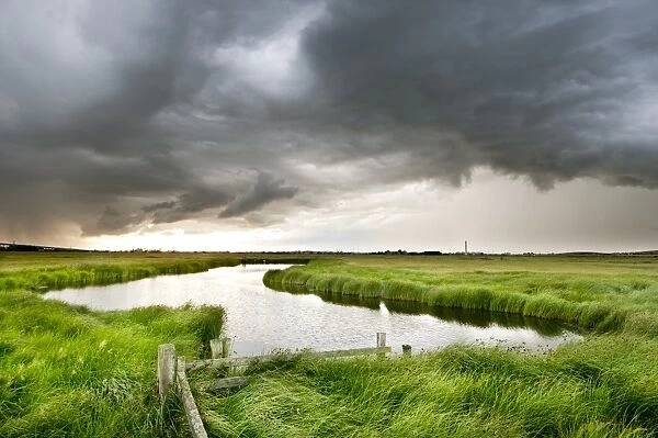 Stormclouds over pool in coastal grazing marsh habitat, Elmley Marshes National Nature Reserve, Isle of Sheppey, Kent