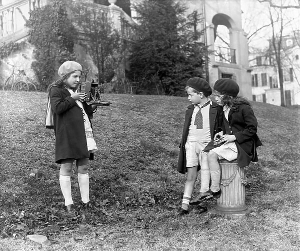 YOUNG PHOTOGRAPHER, c1915. A young girl photographs her two friends, in Washington, D