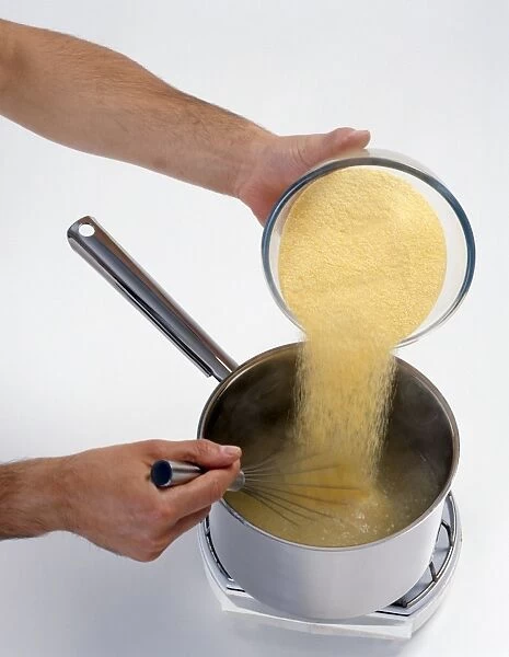 Adding cornmeal to saucepan of water and whisking (making polenta), close-up