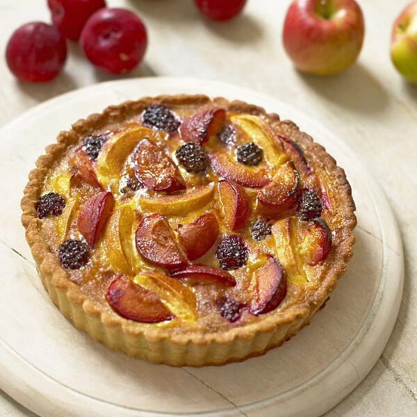 Apple and plum tart on chopping board, close-up