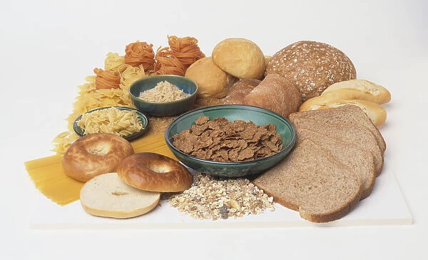 Assorted breads, whole and sliced, breakfast cereal, cooked rice and pasta in bowls, uncooked pasta and plain bagel