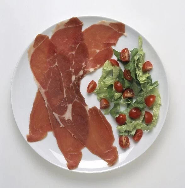 Bayonne ham with lettuce and sliced cherry tomato salad served on white plate