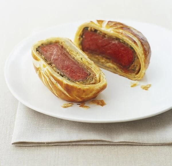 Beef Wellington, cut in two halves, showing rare-cooked fillets inside pastry parcels