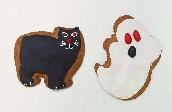Biscuits iced and shaped as a ghost and a black cat, close up
