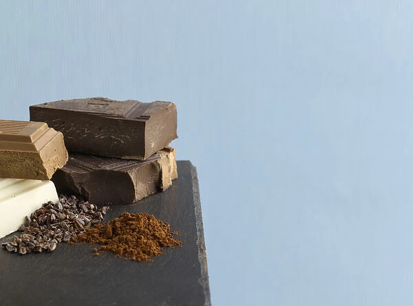 Blocks of white chocolate, milk chocolate and dark chocolate, crushed cocoa beans and cocoa powder