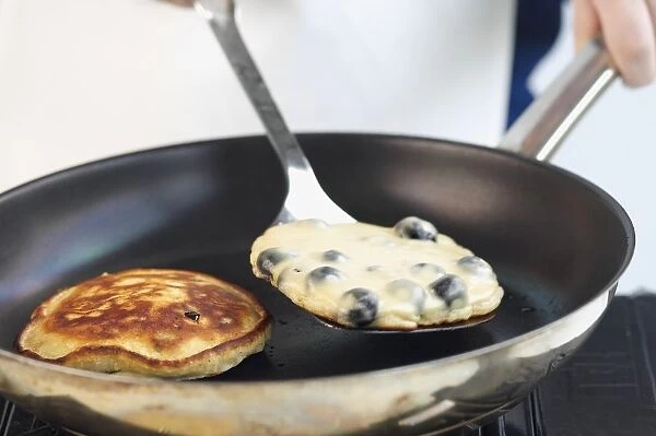 Blueberry pancakes in frying pan and on spatula