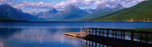 This is a boat dock at Lake McDonald. The blue water of the lake surrounds the dock with mountains in the background
