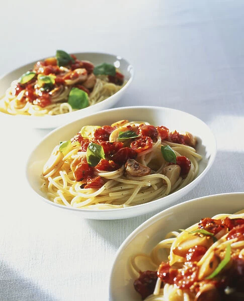 Three bowls of spaghetti topped with vegetables and herbs