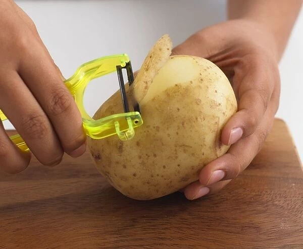 Boy using peeler to peel raw potato