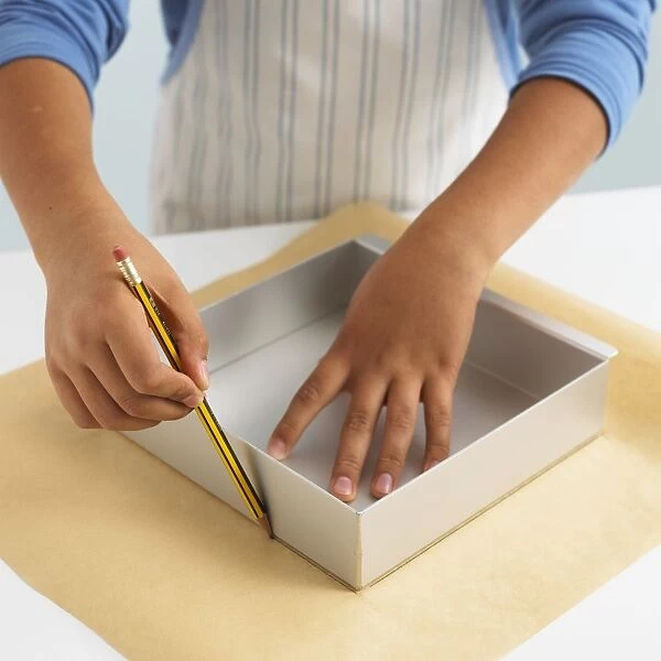 Boy using pencil to draw outline of box on wax paper
