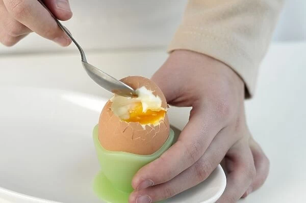 Boy using teaspoon to break top off boiled egg