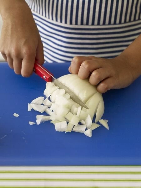 Boys hands chopping onion with kitchen knife, close-up