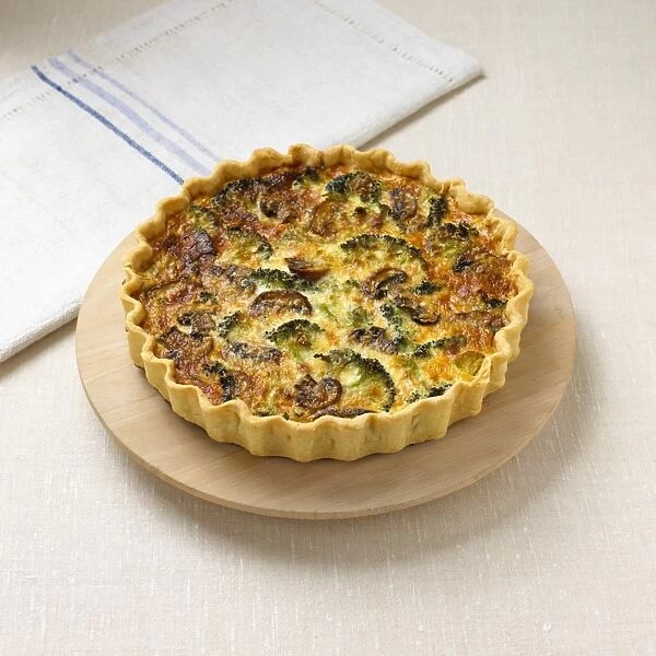 Brocoli and mushroom quiche served on wooden plate with napkin