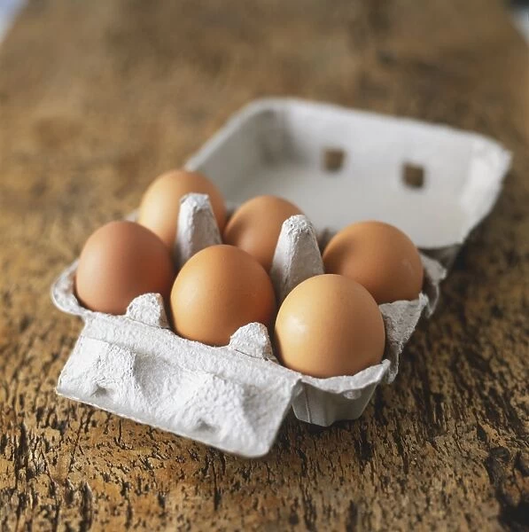 Six brown eggs in an opened carton box, close up