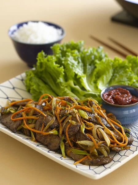 Bulgosi ssambap, Korean lettuce wrap made with beef and strips of onion and carrot, served as separate ingredients on a plate, with spicy bean paste and bowl of rice