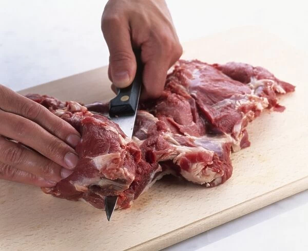 Butterflying leg of lamb using knife to make cut along thick part of meat next to hole left by bone