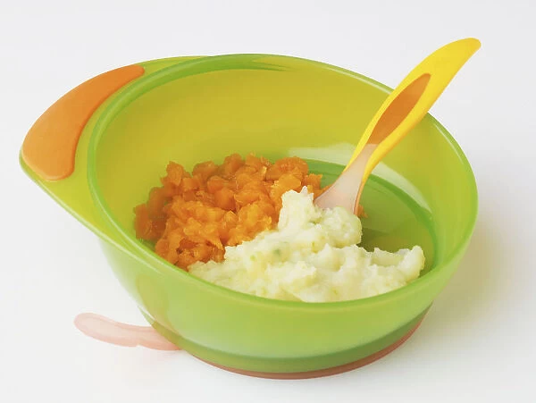 Carrot and potato puree served in green plastic bowl with yellow plastic spoon embedded