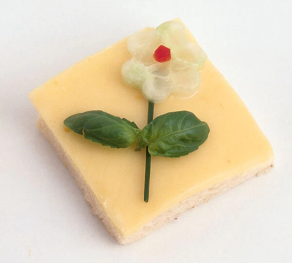 Cheese open sandwich garnished with a flower decoration made from herbs and cucumber
