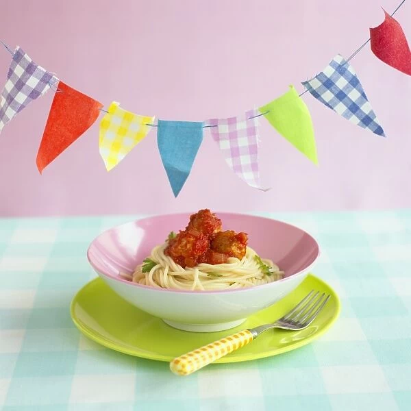 Childrens pasta bowl of chicken balls with spaghetti and tomato sauce with bunting above