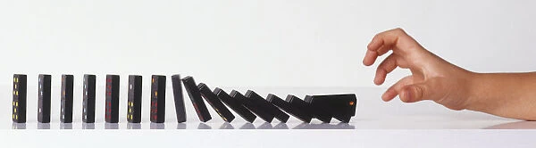 Childs hand pushing over a row of dominoes