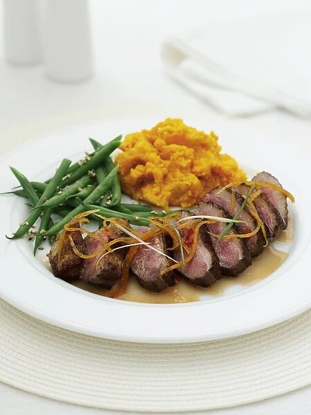 Chilli and orange duck on plate with carrot mash and beans, close-up
