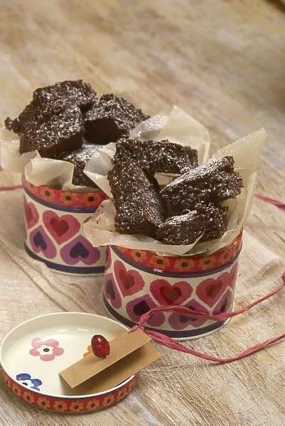 Chocolate brownies in tins surrounded by greaseproof paper