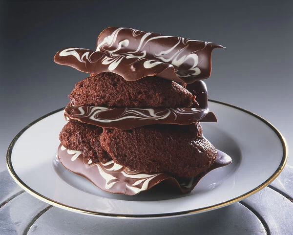 Chocolate dessert on a gold-rimmed plate, stacked chocolate curls filled with mousse, close up