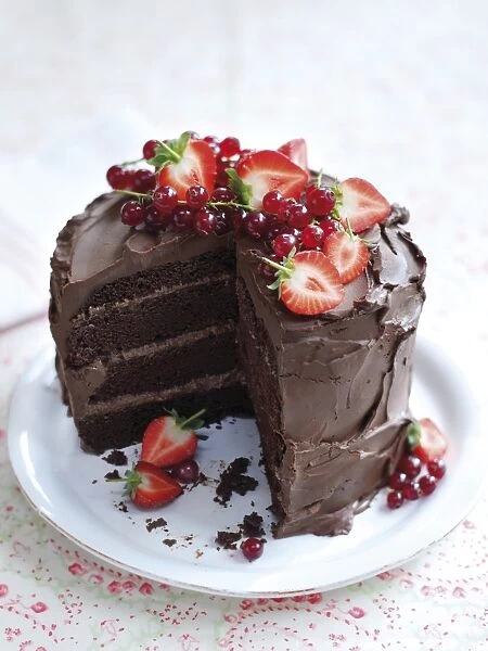 Chocolate layer cake decorated with strawberries and redcurrants