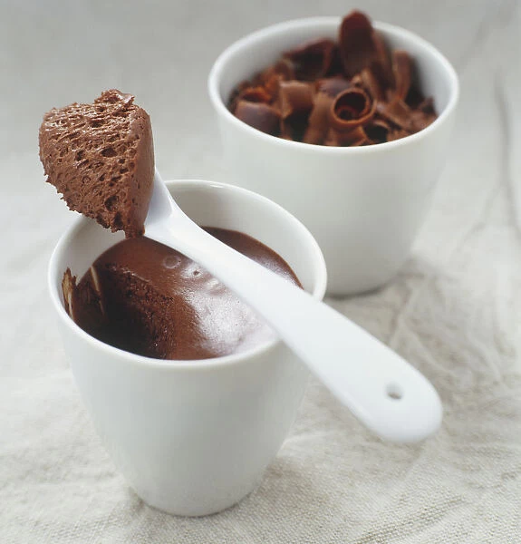Chocolate mousse and chocolate curls in dessert mugs, close up