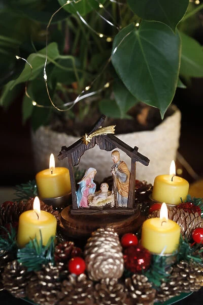 Christmas crib and natural advent wreath or crown with four burning yellow candles