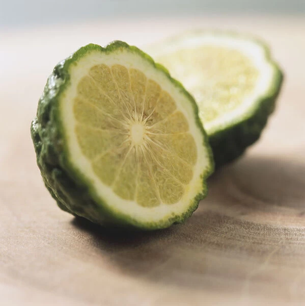 Citrus hystrix, Kaffir Lime, two halves, focus on front half, green zest, yellow flesh