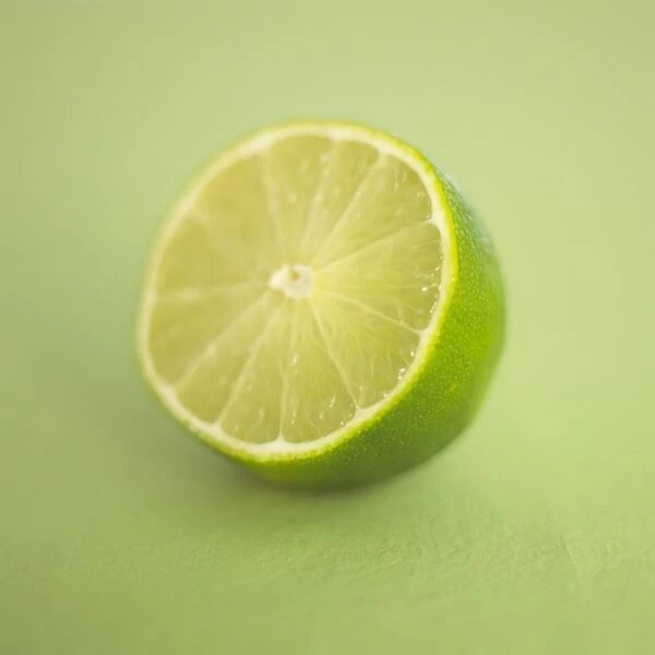 Citrus sp. Lime, green citrus fruit, halved, green soft focus background