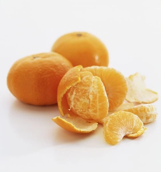 Three clementines, one peeled and partially split into segments, close up
