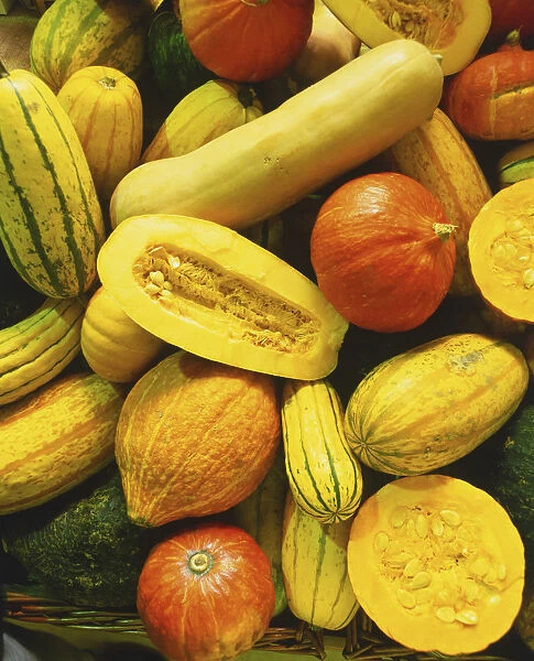 Close-up of whole pumpkins and other squashes, one sliced in half showing the inner flesh and seeds