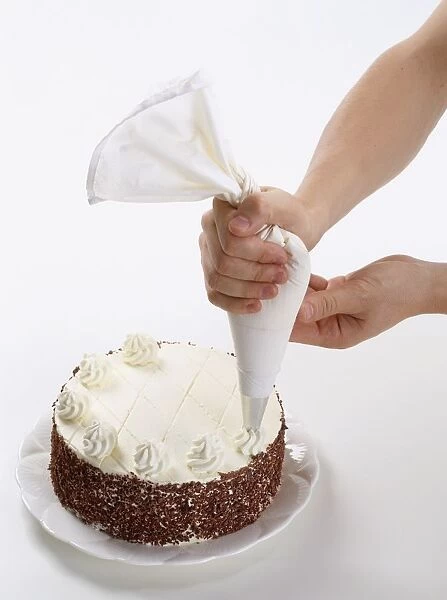 Cream rosettes being piped onto the top of a black forest cake