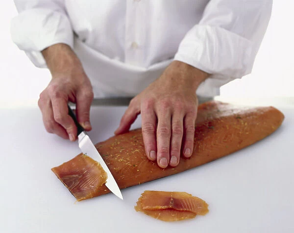 Cutting a fillet of cured salmon into thin, diagonally cut slices