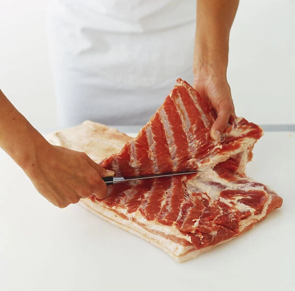 Cutting lengthways through flat slice of raw pork