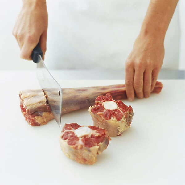 Cutting raw bone of beef into slices