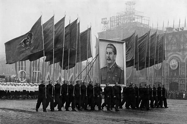 A demonstration  /  parade of the working people in red square in moscow on november 7, 1950, the sportsmen are carrying soviet flags and an image of stalin