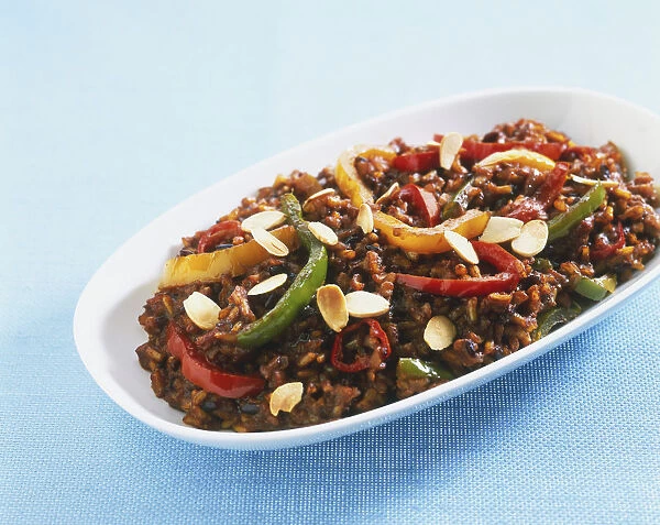 Dish of brown rice with sliced peppers and almond flakes