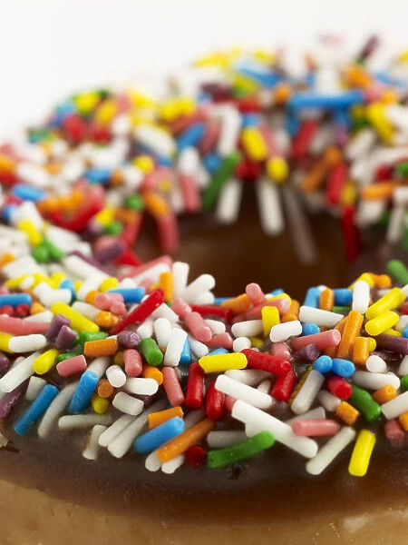 Doughnut with chocolate icing and colourful sprinkles, close-up