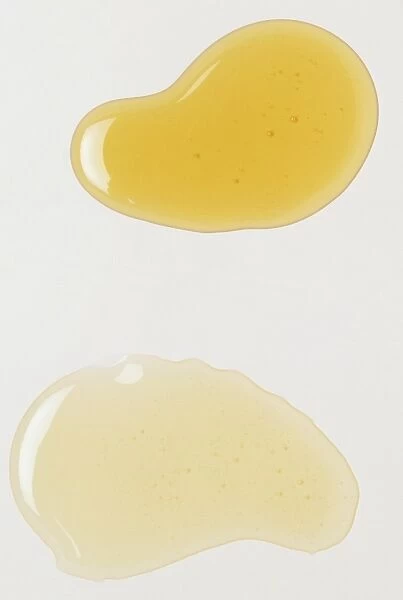 A droplet of yellow oil beside a droplet of colourless oil