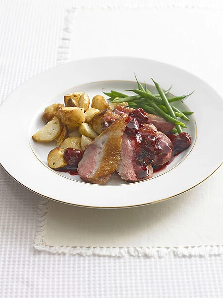 Duck with cherries and vegetables on plate, close-up