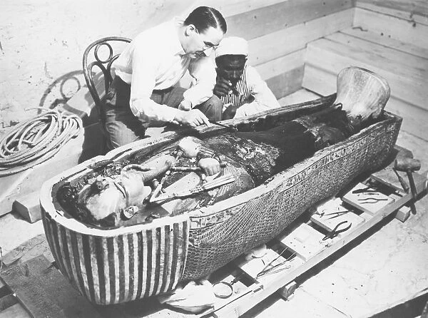 Egypt, Valley of the Kings, The discovery of the tomb of Pharaoh Tutankhamun (or Tutankhamen, circa 1340-1323 B. C. archaeologist Howard Carter (1874-1939) examining the third mummy-shaped sarcophagus, 1922, vintage photograph