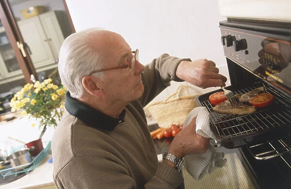 Elderly man cooking pork chop and tomato on a grill